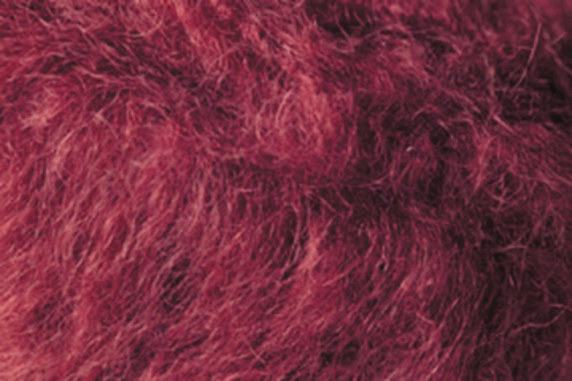 Close-up image of fuzzy, reddish-pink textured fabric, with visible fibers creating a soft and slightly fluffy appearance, reminiscent of the comfort found in Kingfisher Yarn & Fibre's Jo Sharp Rare Comfort Kid Mohair airy sweaters.