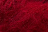 A close-up image of Jo Sharp Rare Comfort Kid Mohair by Kingfisher Yarn & Fibre, showcasing its red fibrous material with a tangled and fuzzy texture. The fibers appear soft and wispy, creating a dense and intricate pattern across the image, resembling wool or synthetic fur.