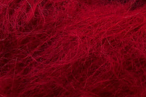 A close-up image of Jo Sharp Rare Comfort Kid Mohair by Kingfisher Yarn & Fibre, showcasing its red fibrous material with a tangled and fuzzy texture. The fibers appear soft and wispy, creating a dense and intricate pattern across the image, resembling wool or synthetic fur.