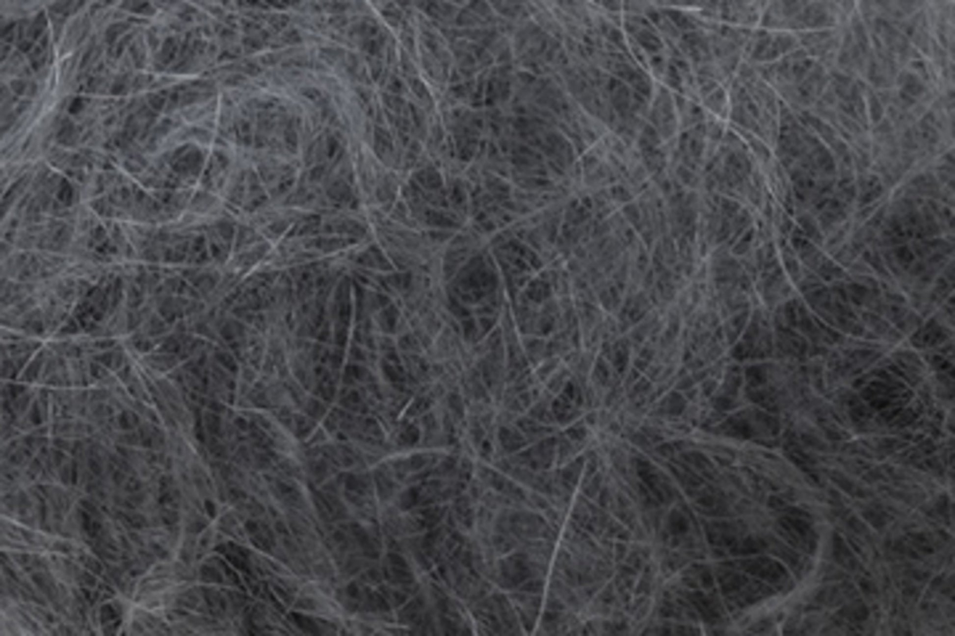 Close-up of a tangled mass of Jo Sharp Rare Comfort Kid Mohair fibers from Kingfisher Yarn & Fibre. The texture appears coarse and intertwined, resembling a bundle of hair or fine threads. The image evokes a sense of disarray, with various strands overlapping in an unkempt manner, much like the cozy chaos one might find in airy sweaters.