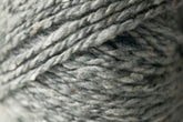 A close-up of a skein of Jo Sharp Silkroad Aran Tweed by Kingfisher Yarn & Fibre. The yarn looks soft and slightly fuzzy, with multiple thin strands twisted together to form a thicker piece. The texture appears rough and woolly, enhanced by rich tweed highlights that add depth and character.