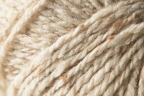 Close-up image of cream-colored wool yarn with slightly speckled, rich tweed highlights. The thick strands are twisted together, revealing the luxurious and soft fibrous nature of this Kingfisher Yarn & Fibre Jo Sharp Silkroad Aran Tweed material.