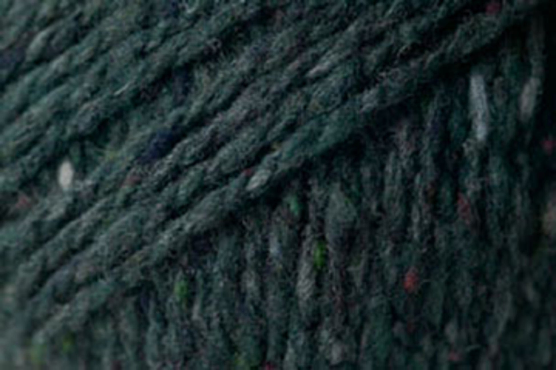 Close-up image of dark green, slightly speckled yarn with a textured, woven appearance. This Kingfisher Yarn & Fibre Jo Sharp Silkroad Aran Tweed yarn features rich tweed highlights, with fibers that appear thick and tightly twisted, creating a dense and rustic look suitable for knitting, crocheting, or other textile crafts.