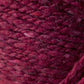 Close-up image of luxurious, burgundy-colored yarn with a slightly textured, woven appearance. The Kingfisher Yarn & Fibre's Jo Sharp Silkroad Aran Tweed fibers showcase varying shades of red with subtle flecks of lighter and darker hues, resulting in rich tweed highlights and a tactile quality.