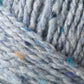 Close-up of the luxurious Kingfisher Yarn & Fibre Jo Sharp Silkroad Aran Tweed yarn featuring specks of blue, beige, and white. The image showcases tightly woven strands forming a textured pattern. The yarn appears soft and slightly fuzzy, making it ideal for knitting or crocheting projects.