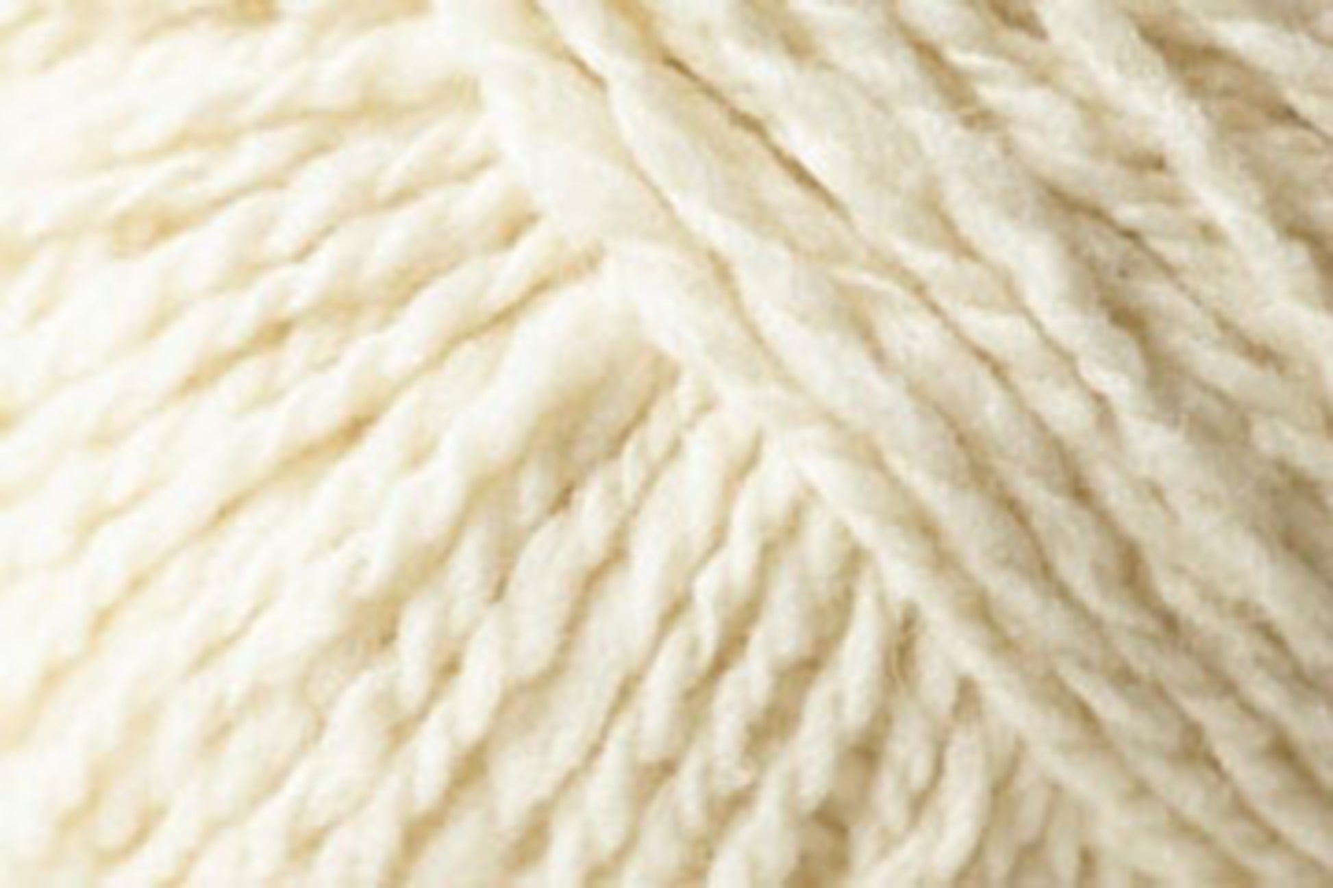 Close-up image of Jo Sharp Silkroad Aran Tweed by Kingfisher Yarn & Fibre, showcasing a ball of luxurious, cream-colored yarn with a soft, slightly fuzzy texture. The strands are twisted together, creating a chunky, cozy appearance with rich tweed highlights.