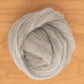 A soft, fluffy ball of light gray Shetland Top Wool Fiber from Europa Wools Ltd is coiled neatly on a wooden surface. The texture appears smooth and slightly fuzzy, making it ideal for crafts like spinning fine yarns or felting.