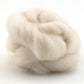 A close-up of Punta Wool Top Fiber by Halcyon Yarn showcases its soft, fluffy texture, ideal for spinning or felting, with light and shadow playing against a plain white background.