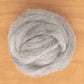 A round, fluffy ball of Icelandic Top Wool Fiber by Europa Wools Ltd, resembling the soft tog fiber from Icelandic sheep, is placed on a wooden surface, showcasing its natural texture.