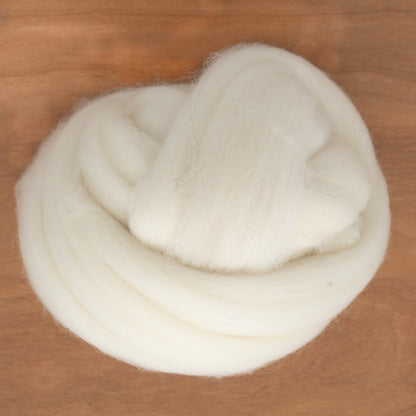 A neatly coiled bundle of RH Lindsay's Fine White Merino Wool Top (sold by the ounce) rests on a wooden surface, perfect for intricate needle felting projects.