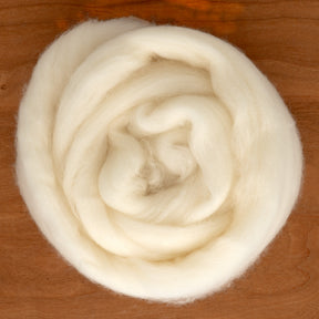 A neatly arranged bundle of Merino Superwash Wool Top by Europa Wools Ltd sits on a wooden surface. The luxurious, white fibers appear soft and fluffy, perfect for spinning or felting projects.