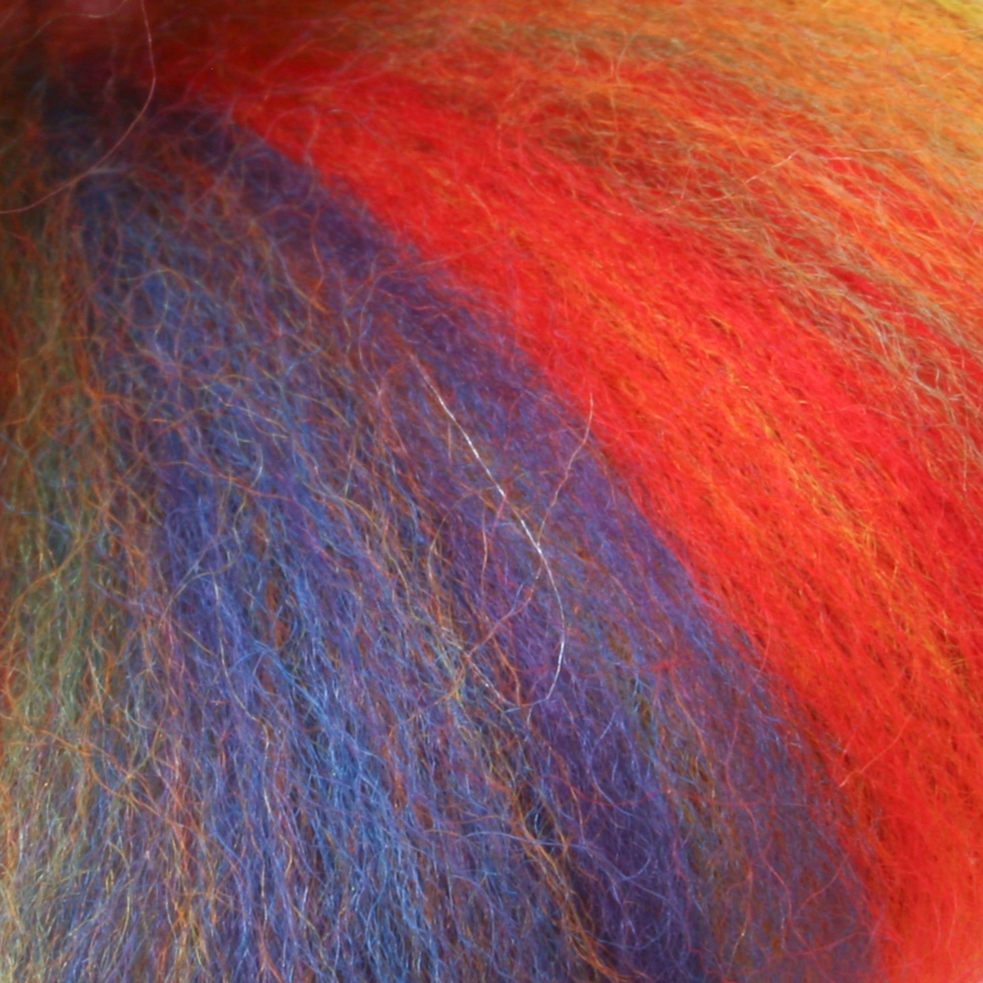 Close-up of the Multi-Colored Merino Wool Top by Europa Wools Ltd, showcasing its fluffy fibers in vibrant shades of red, orange, blue, and green for a soft and textured appearance.