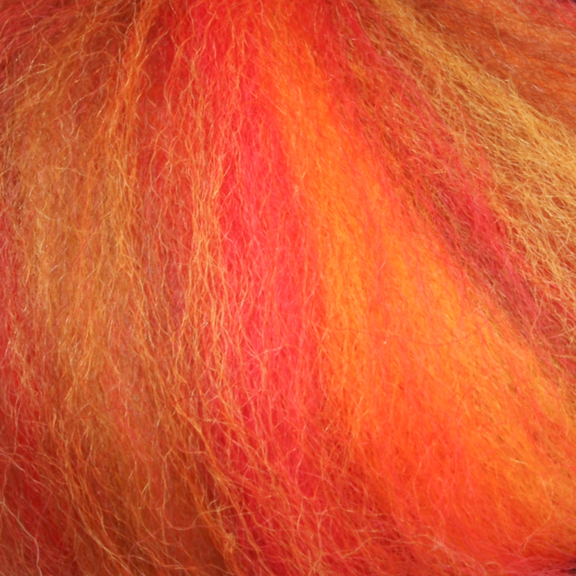 Close-up of vibrant fiber strands in shades of orange, red, and yellow that bring to mind the Multi-Colored Merino Wool Top from Europa Wools Ltd. The warm, fiery pattern appears soft and fluffy, similar to genuine merino wool.