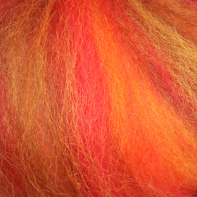 Close-up of vibrant, multicolored fibers showcasing the red, orange, and yellow hues of Europa Wools Ltd's Multi-Colored Merino Wool Top. The texture is soft and fluffy, with a tangled and layered appearance reminiscent of cozy merino yarns.