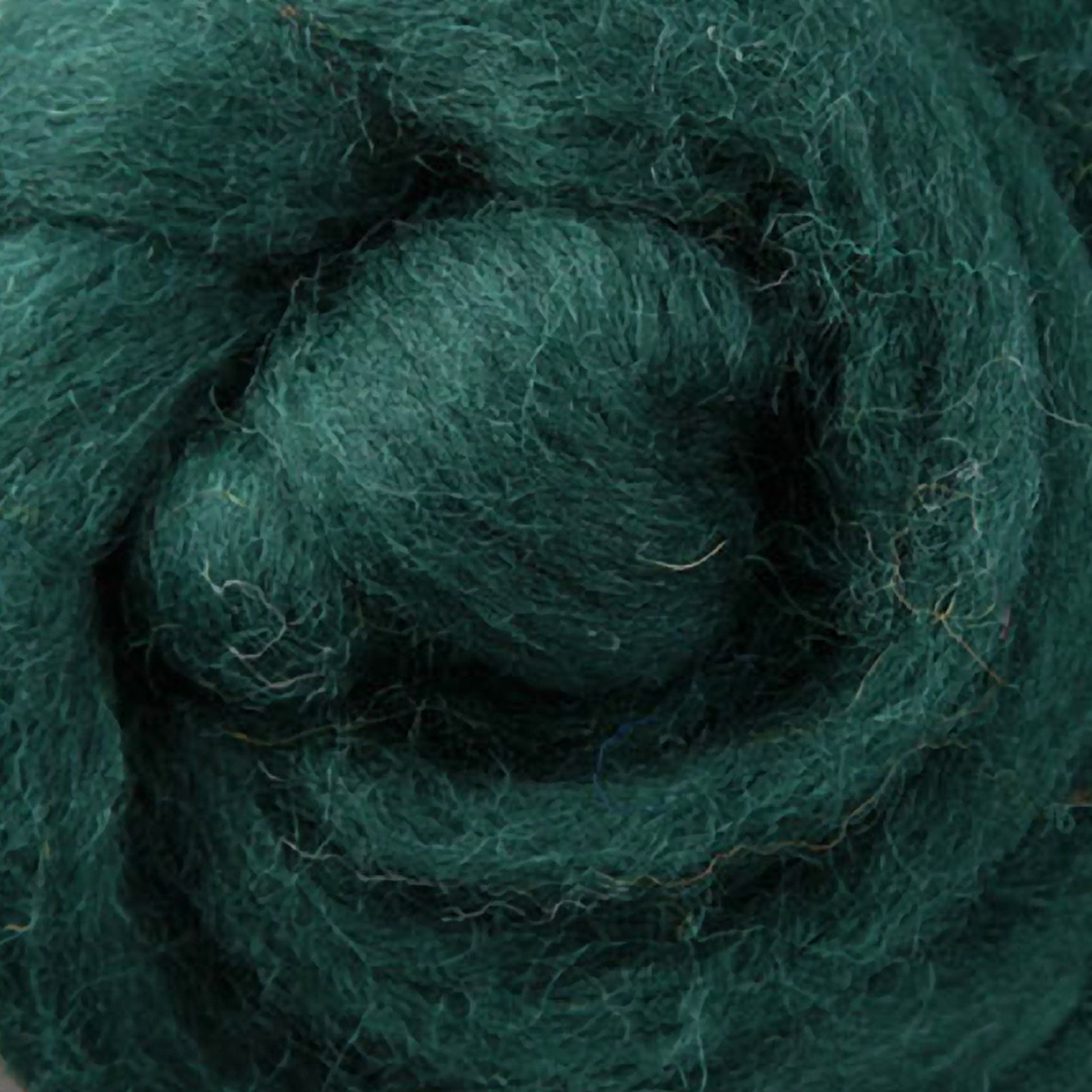 Close-up of Ashford Handicrafts Limited's Corriedale New Zealand Wool Fiber to Spin and Felt, sold by the ounce, featuring tightly coiled dark green fibers in a spiral pattern that highlight its soft and textured surface.