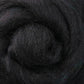 A detailed view of Ashford Handicrafts Limited's Corriedale New Zealand Wool Fiber to Spin and Felt, showcasing tightly wound spirals. The soft and slightly fuzzy fibers reveal deep charcoal tones with subtle accents of other dark hues, making it perfect for spinning or crafting projects. Available by the ounce.