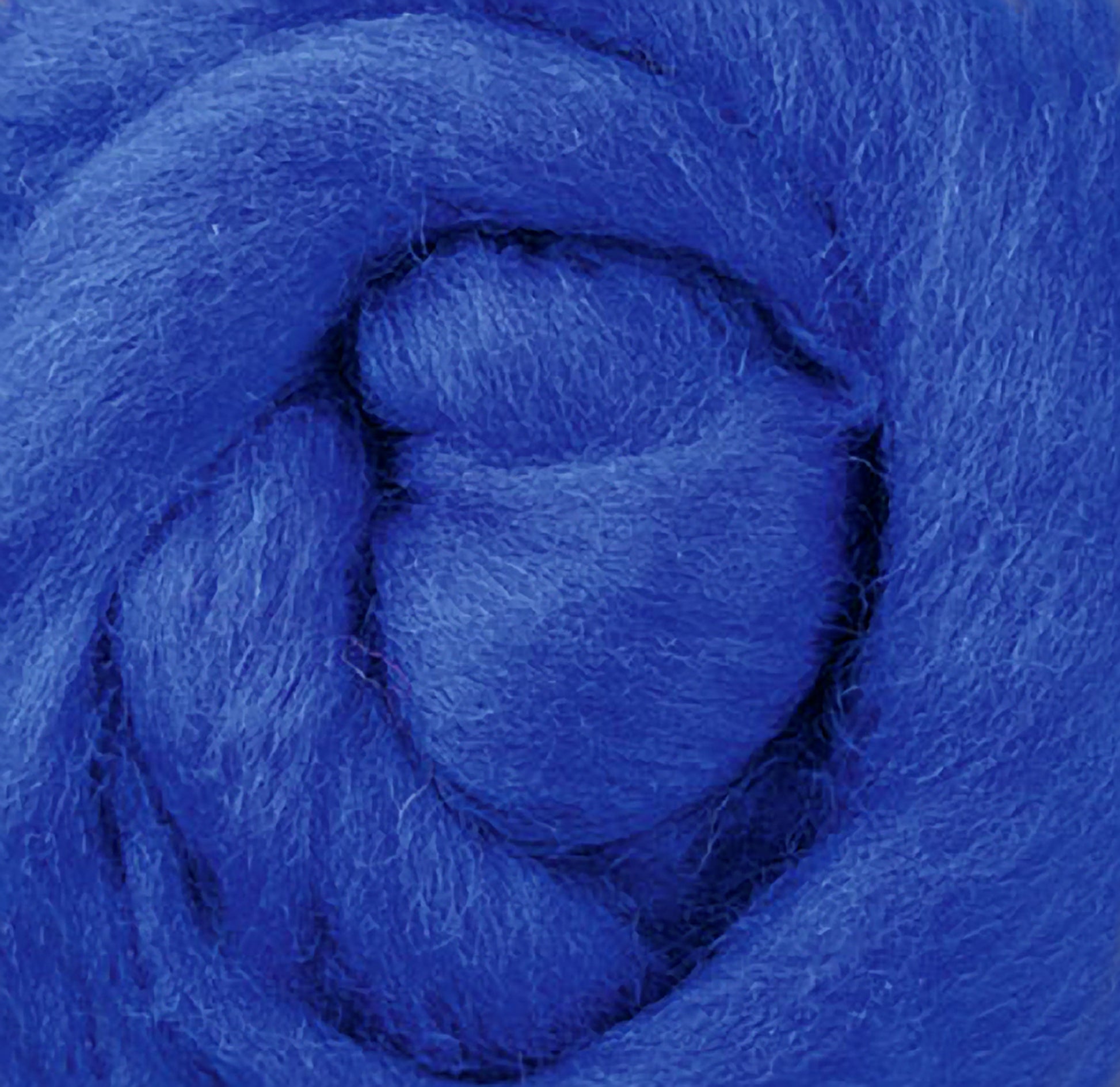 A close-up image showcases the Ashford Handicrafts Limited Corriedale New Zealand Wool Fiber to Spin and Felt, featuring soft and thick blue fibers tightly wound in a circular pattern. The various shades of blue create depth and dimension, making it ideal for felting projects.