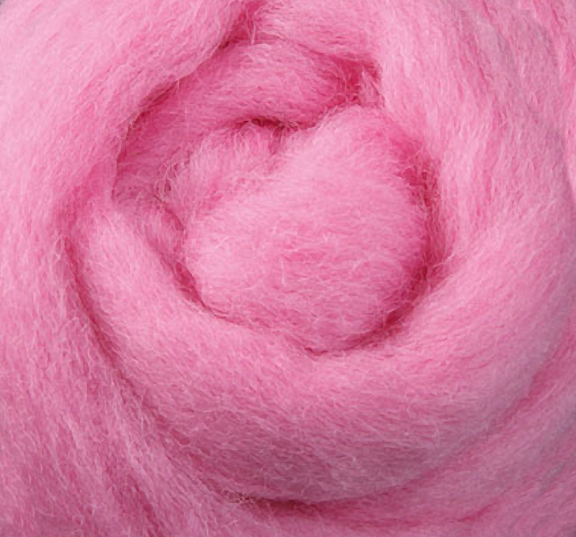 Close-up of Corriedale New Zealand Wool Fiber from Ashford Handicrafts, spiraled into a circular shape. The soft, fluffy pink wool appears airy and light, ideal for spinning and crafting projects.