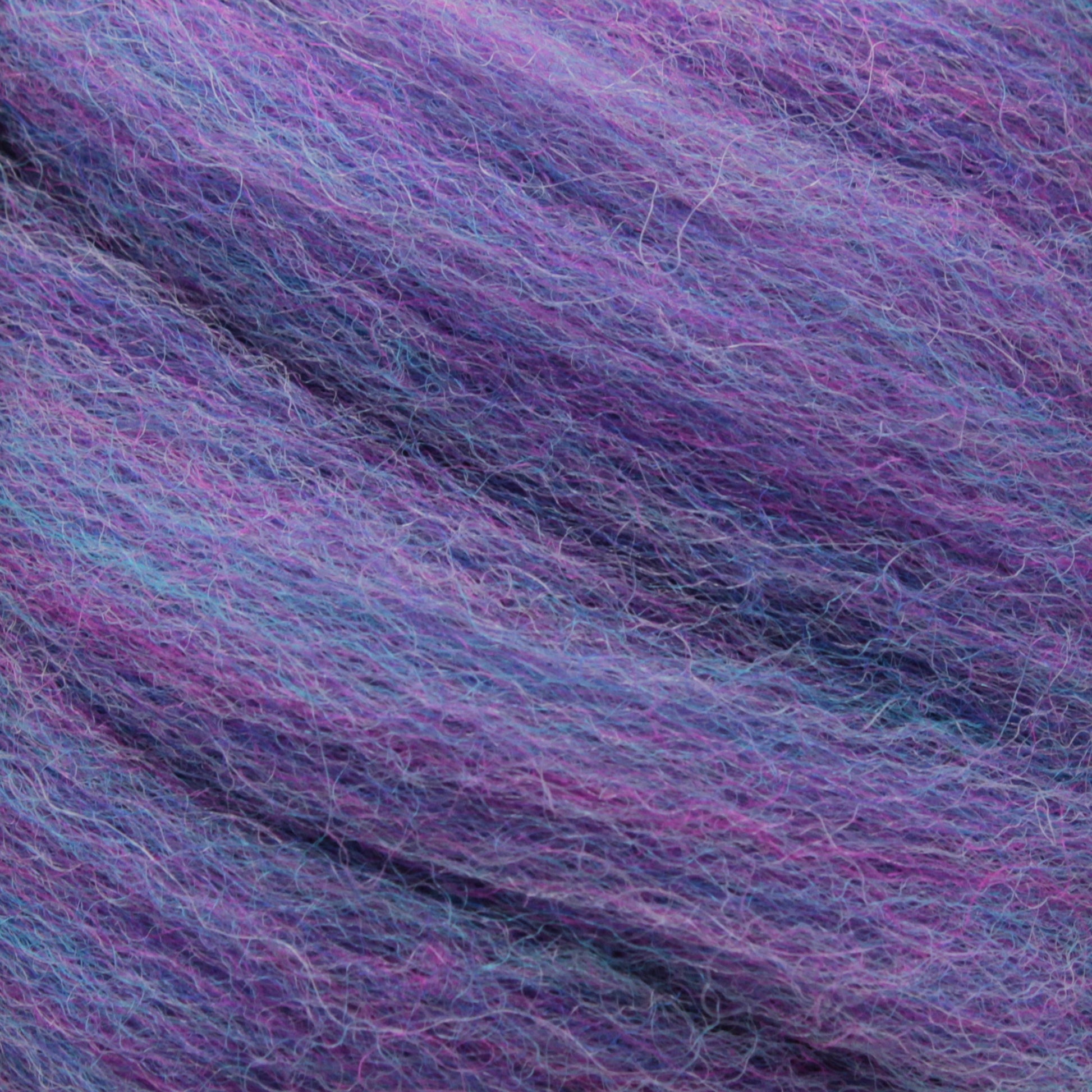 Close-up image of Kraemer's Mauch Chunky Roving. This yarn showcases a blend of purple, blue, and pink hues, resulting in a soft, multicolored texture ideal for needle and wet felting. The fibers are thick and slightly fuzzy, emphasizing the intricate detail of the wool strands.