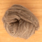 A ball of Europa Wools Ltd's Yak Down Fiber, a luxuriously soft brown wool roving blended with yak fiber, sits on a wooden surface.