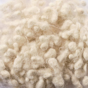 Close-up of a pile of raw, white Wool Nepps by Europa Wools Ltd. The wool appears fluffy and soft, with a slightly tangled texture and individual fibers visible. This unique yarns scene is well-lit, highlighting the natural off-white color and fibrous details of the Wool Nepps.