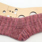 The Classic Socks by Yankee Knitter Designs are showcased on a wooden sock blocker to maintain their shape. These hand-knitted, ribbed socks come in a delightful blend of various shades of pink, creating a beautiful marled effect. The versatile pattern is available for download and can be made in sizes from baby to adult using different yarn weights.