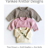 Three knitted raglan sweaters in gray, pink, and cream are neatly stacked on a white background. The caption reads “‘Top Down Roll Raglan for Kids’ by Yankee Knitter Designs.” This seamless knit child’s pullover pattern is available in sizes ranging from 6 months to 12 years and uses worsted weight yarn with a gauge of 5 stitches per inch.