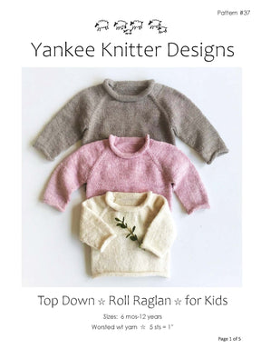 Three knitted raglan sweaters in gray, pink, and cream are neatly stacked on a white background. The caption reads “‘Top Down Roll Raglan for Kids’ by Yankee Knitter Designs.” This seamless knit child’s pullover pattern is available in sizes ranging from 6 months to 12 years and uses worsted weight yarn with a gauge of 5 stitches per inch.