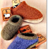 Three Bryson Distributing, Inc. Child's Felt Clogs in brown, grey, and purple are arranged among orange blocks featuring various letters and animal illustrations. Perfect for children, each handmade slipper includes double soles for extra comfort. The background is a soft beige fabric.