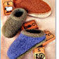 Two pairs of Bryson Distributing, Inc.'s Child's Felt Clogs: one in brown and the other in blue and green hues, placed on a soft surface. These felt clog slippers with double soles sit next to picture flashcards, each displaying a letter and image, including "L," "C," and "S" depicting a lamb, cow, and spinning wheel—perfect for children.