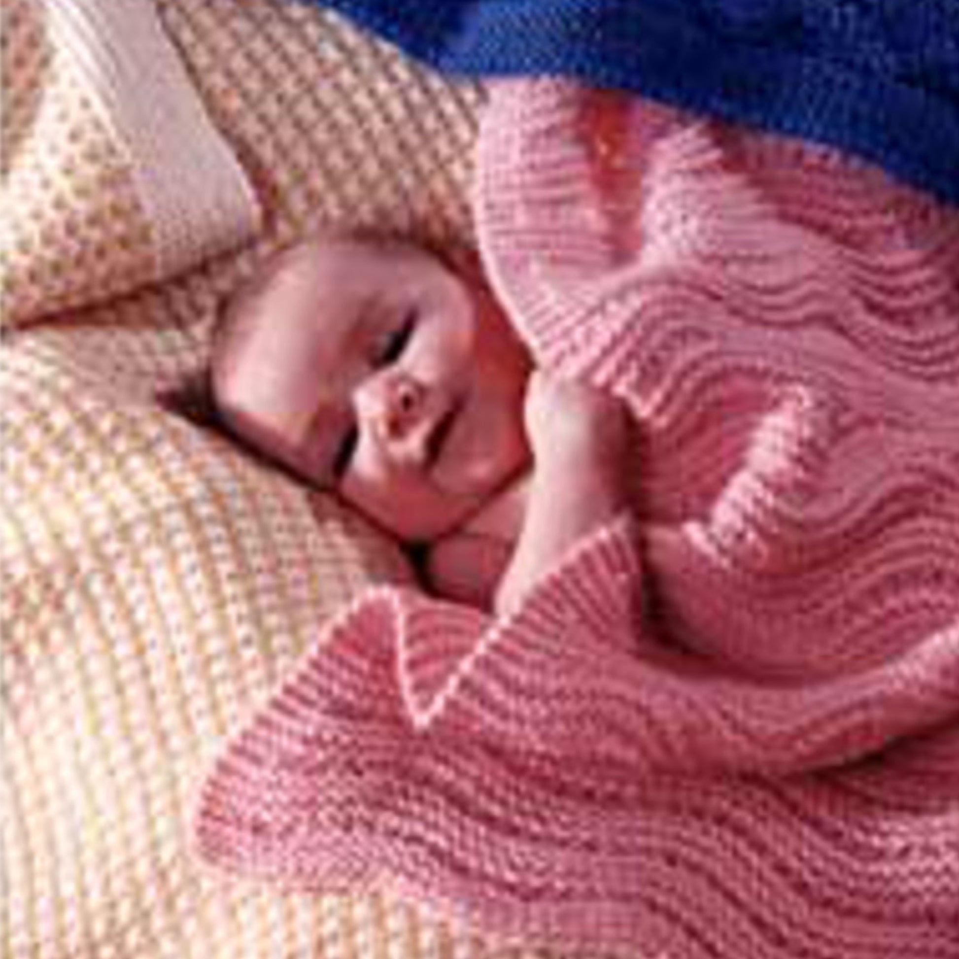 A baby with a joyful expression is lying on a soft, patterned yellow blanket, partially covered with the Three Easy Baby Blankets in pink from Bryson Distributing, Inc. The baby is looking up and appears to be nestled comfortably in the cozy surroundings.