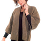 A person with curly hair is wearing the Basic Garter Stitch Kimono, a brown knitted cardigan from Plymouth Yarn Co, over a black long-sleeved outfit made from worsted weight yarn. The kimono has wide sleeves and an open front, and the individual has a slight smile while holding it near the neck with one hand.