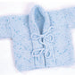 The Plymouth Yarn Co Baby Kimono is a small, hand-knitted baby cardigan in light blue yarn with speckles of darker blue. This stylish piece features long sleeves, a fold-over collar, and ties at the front for fastening. The knitting pattern showcases a dense, textured garter stitch.