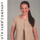 A person with long dark hair smiles while wearing the Loose Knit Swing Cardigan Pattern from Plymouth Yarn Co. This stylish, light brown, short-sleeved cardigan is crafted from soft alpaca yarn and features buttons and a pleated design over a tank top. The background is plain, and "UTH YARN COMPANY" text appears on the left.