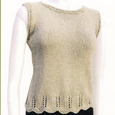 The Chevron Trim Top from Knit One, Crochet Too is a hand-knitted, sleeveless beige top displayed on a mannequin. It features a simple knit pattern with a delicate chevron lace design along the bottom hem and around the armholes and neckline.