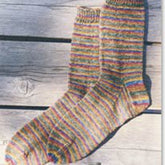 A pair of Beginner's Lightweight Socks from Bryson Distributing, Inc., featuring multicolored horizontal stripes in shades of red, blue, yellow, and green on wool fabric, laid out side by side on a light, weathered wooden surface.