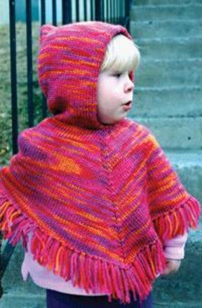 A little one stands outdoors on steps, wearing the Bryson Distributing, Inc. Children's Hooded Poncho in vibrant shades of red, orange, and pink. The fashion-forward poncho features a hood and fringes along the bottom edge. The child appears to be looking to the side with their mouth slightly open.