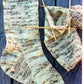 A completed Men's Heavy Weight Boot Sock from Bryson Distributing, Inc. with a beige and brown pattern rests on a blue wooden surface beside a second sock in progress. Crafted from worsted weight yarn, these heavy boot socks fit men's shoe sizes 7 to 12. Wooden knitting needles are inserted into the unfinished sock, while a ball of yarn lies adjacent.