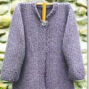 An Autumn Coat by Bryson Distributing, Inc. hangs on a wooden coat hanger, showcasing its warm, hand-knitted grey texture. This comfortable cardigan features long sleeves, a round neckline, and a single button closure at the top. In the background lies a rustic stone wall.