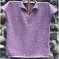 Displayed against a stone wall background is the Bistro Shirt Pattern from Bryson Distributing, Inc. It's a purple knitted pullover featuring a short collar and V-neck. The coarse texture lends it a handmade and cozy appearance.