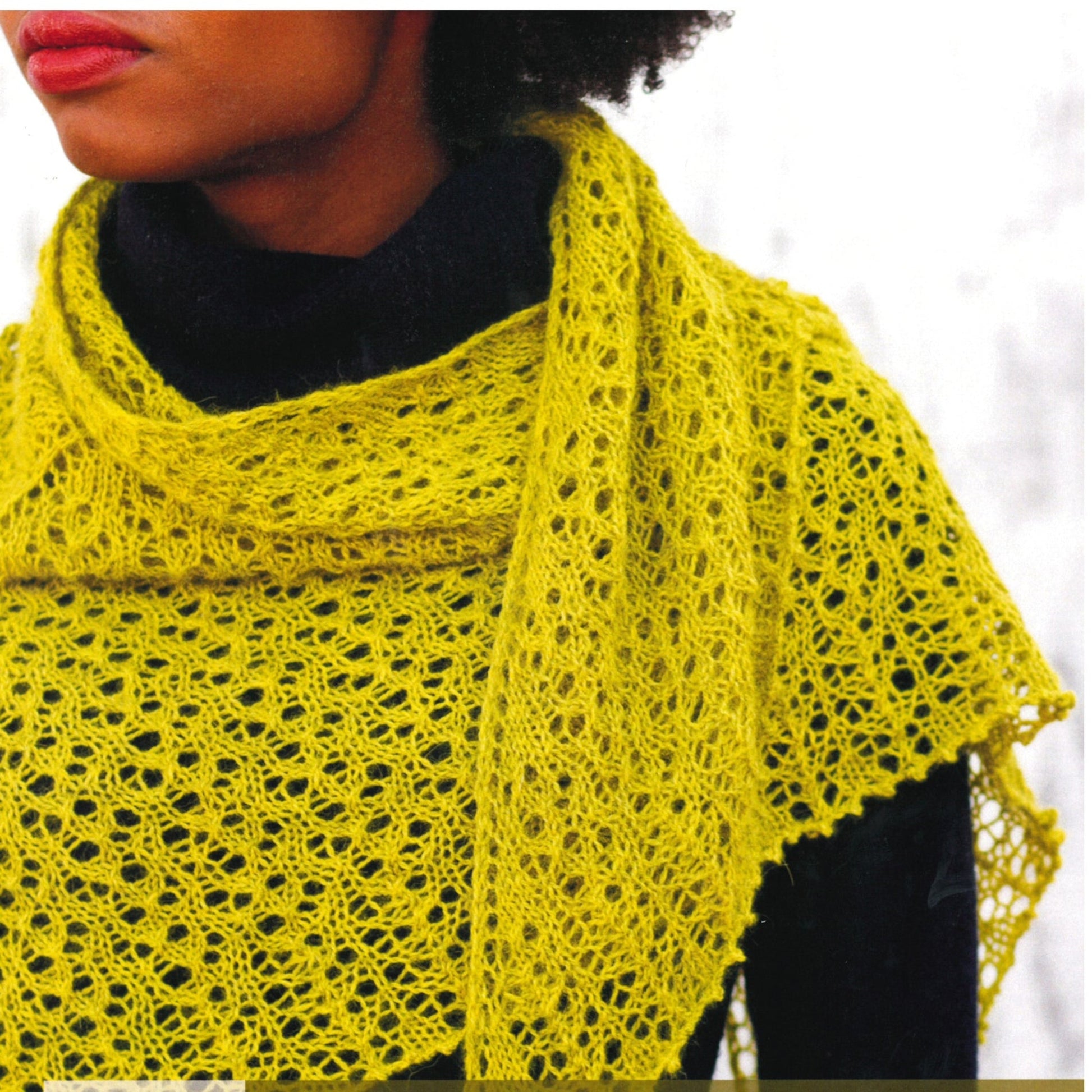 A person wearing a handcrafted, lightweight Tangled Lace Shawl from Knitting Fever / Euro Yarns in lime-green is draped over a black top. Only the lower half of the face and torso are visible, showcasing the intricate detail and texture of the fingering weight alpaca shawl. The background is out of focus.