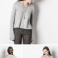 In the top photo, a woman is wearing a light grey Spring Hill Sweater from Blue Sky Fibers, made with organic cotton worsted yarn, paired with dark grey pants as she looks down. Below it are two smaller photos: one displaying the back of her outfit and another showing a side view of her looking down. Her long hair is tied at the back.