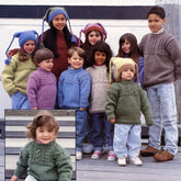 A group of children are standing outdoors, donning vibrant, Guernsey-style knitted sweaters and hats with intricate patterns from the Colorful Kids #402 collection by Halcyon Yarn. The children, who vary in age and size, wear an array of sweaters in colors such as green, lavender, yellow, red, and gray. Inset: a toddler is seen in a bulky-gauge green sweater from the same collection.