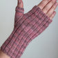 A hand wearing Lisa's Knits' Fingerless Gloves and Mitts, Fingering Weight, made of pink and gray variegated yarn. The glove features a ribbed pattern with an open thumb hole, leaving the fingers free. Crafted from high-quality fingering weight yarn, these gloves are showcased against a plain light-colored background.