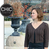 A woman wearing a black shirt and the CeCe Cardigan, a brown knitted piece featuring a delicate lace pattern, stands outdoors near a large decorative urn with autumnal branches. The image showcases the Chic Knits logo in the top left corner. She has short, wavy hair and is looking to the right.