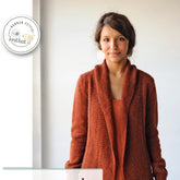 A person wearing a Knitbot Autumnal Cardigan from Never Not Knitting and a matching top stands against a plain background. The logo in the top left corner features the text "HANNAH FETTIG knitbot" next to a graphic of knitting needles and yarn, perfect for a cozy weekend cover-up.