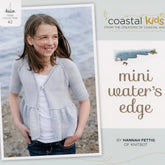 A young girl stands by the seaside wearing a light gray Mini Water's Edge Cardigan over a white shirt. The image graces the cover of a knitting book titled "Coastal Kids Mini Water's Edge Cardigan," authored by Hannah Fettig and available for download. Published under the Never Not Knitting brand, this cardigan is perfect for all seasons and makes an ideal addition to any little girl's wardrobe, with water and rocks providing a picturesque background.