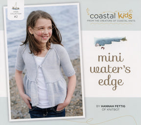 A young girl stands by the seaside wearing a light gray Mini Water's Edge Cardigan over a white shirt. The image graces the cover of a knitting book titled "Coastal Kids Mini Water's Edge Cardigan," authored by Hannah Fettig and available for download. Published under the Never Not Knitting brand, this cardigan is perfect for all seasons and makes an ideal addition to any little girl's wardrobe, with water and rocks providing a picturesque background.