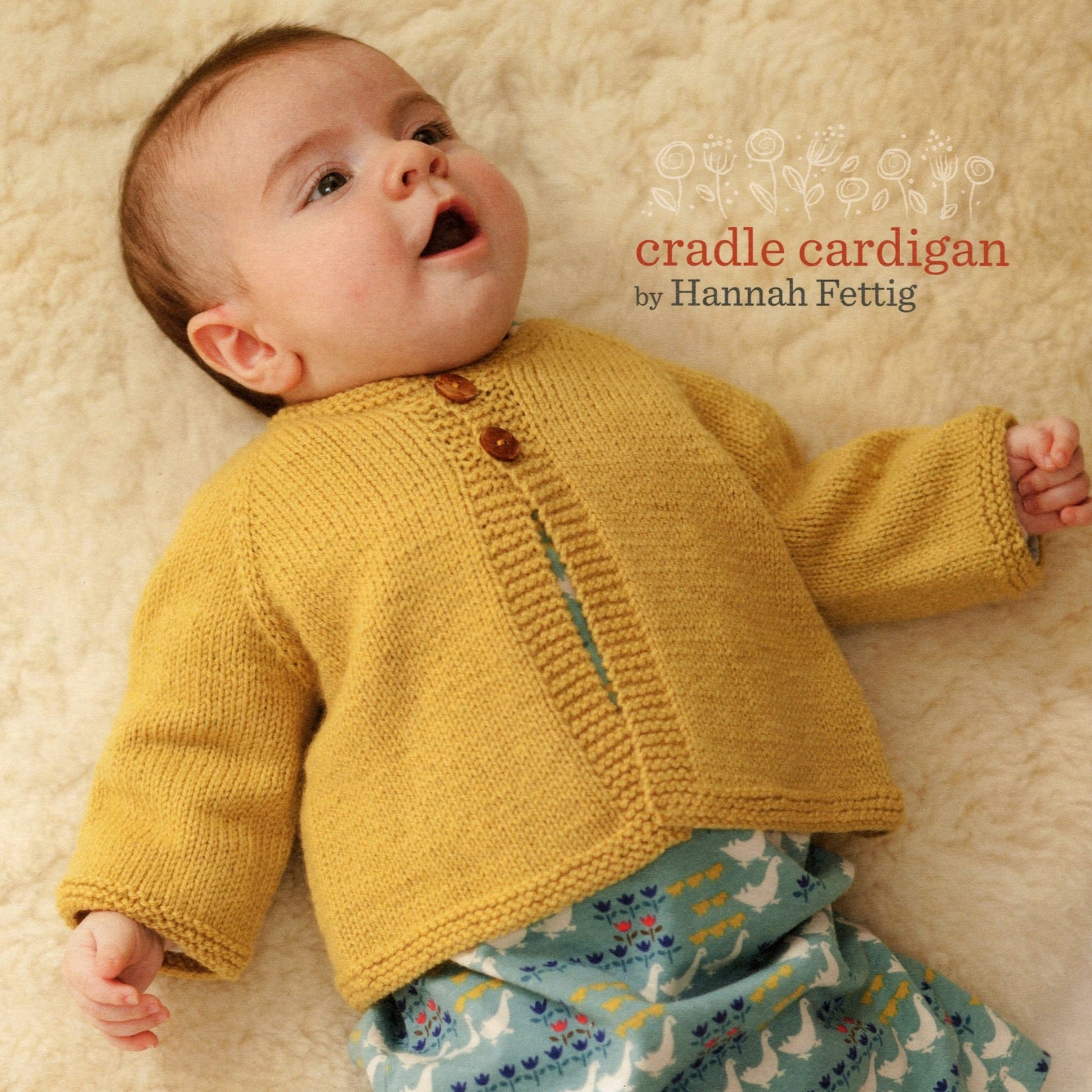 A baby lies on a soft, cream-colored surface, wearing a mustard yellow knitted classic top down cardigan and patterned pants. The text "Mabel's Closet Cradle Cardigan by Never Not Knitting" is written to the right of the baby's head in orange and purple fonts.