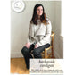 A woman with long dark hair is seated on a white chair, smiling warmly. She is dressed in a light-colored worsted weight cardigan from Never Not Knitting's Knitbot collection, paired with a white blouse and black pants. Text reads, "Knitbot Harborside Cardigan by Never Not Knitting. This eclectic set-in sleeve design fits well to your shoulders, with waterfall fronts that feel like a hug!